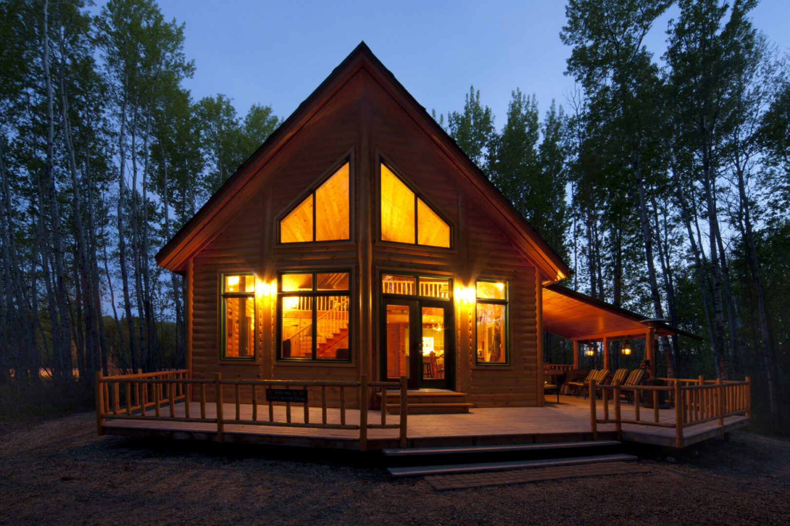 Wooden cabin illuminated at twilight in forest.