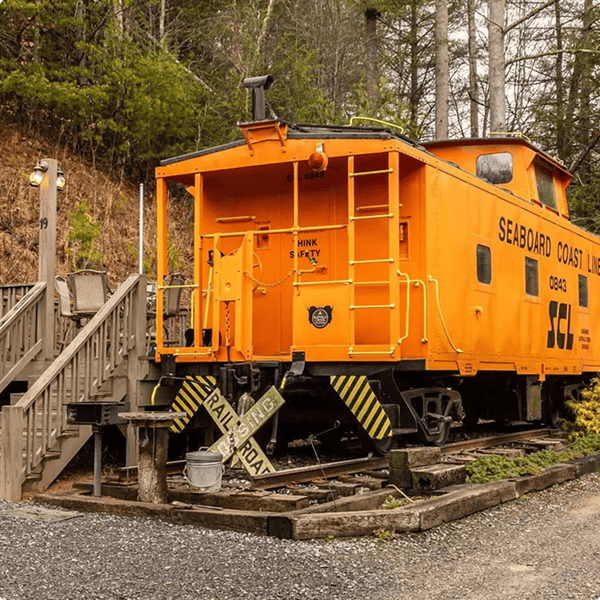 Orange caboose beside a wooden platform.