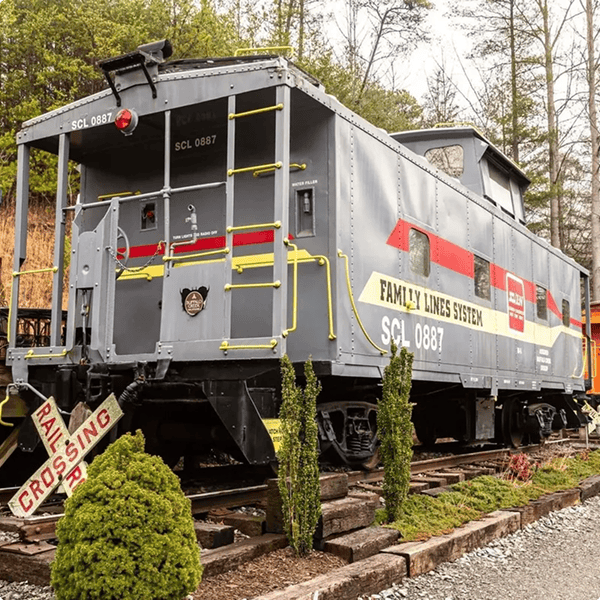Gray caboose on display with trees.
