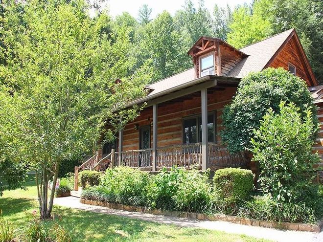 Rustic log cabin surrounded by lush greenery.