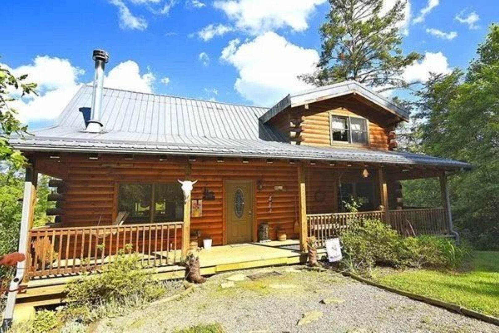 Log cabin with porch in sunny setting.