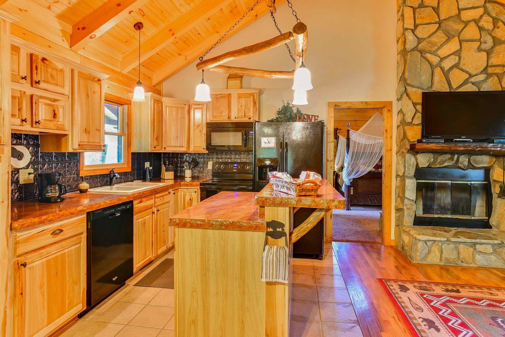 Rustic kitchen with wooden cabinets and fireplace.