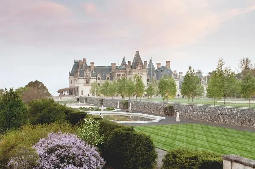 Historic mansion with manicured gardens and lawn.