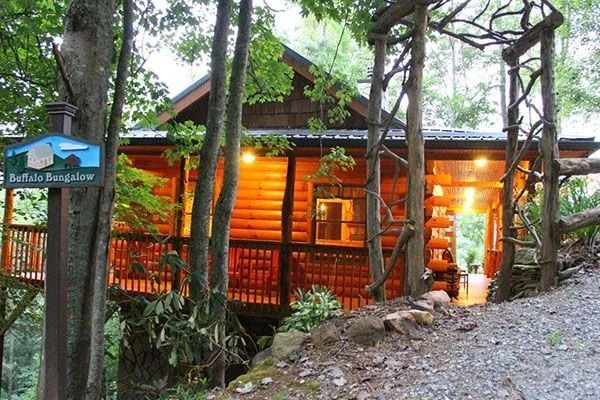 Log cabin with glowing lights amidst trees.