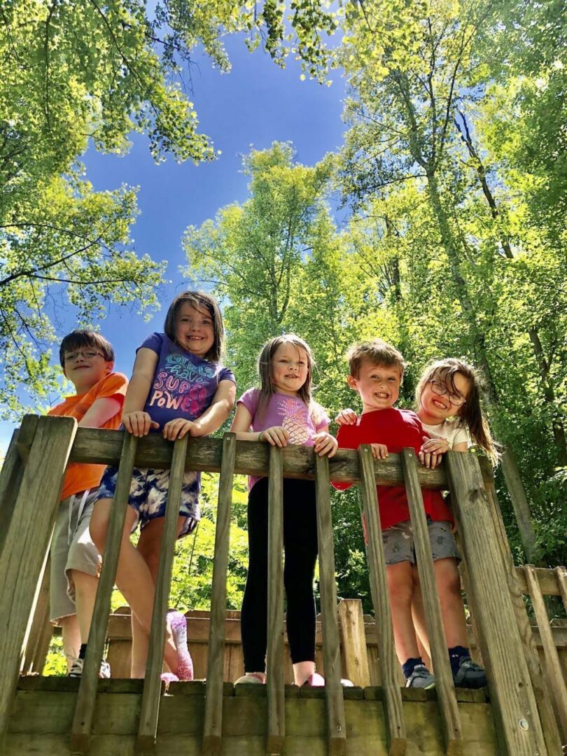 Children playing on wooden structure, sunny day.