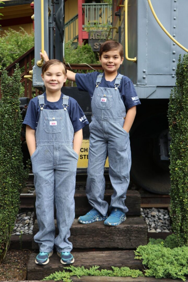Two children in striped overalls smiling.