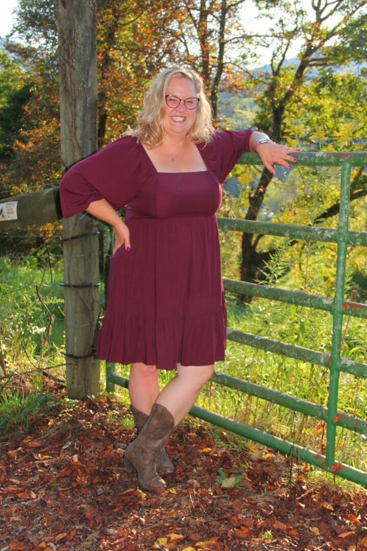 Woman in maroon dress near green gate.