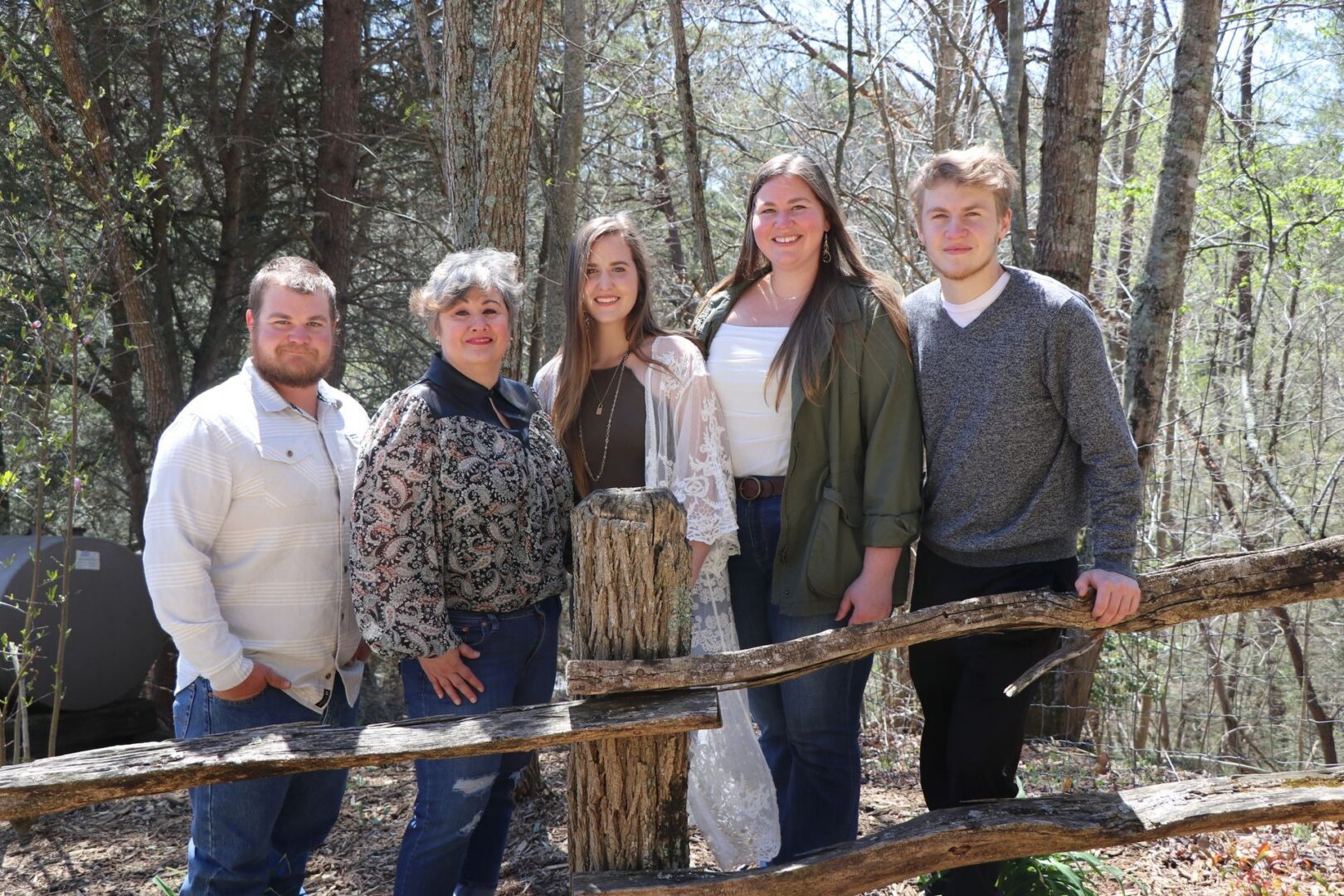 Group posing by rustic wooden fence outdoors.