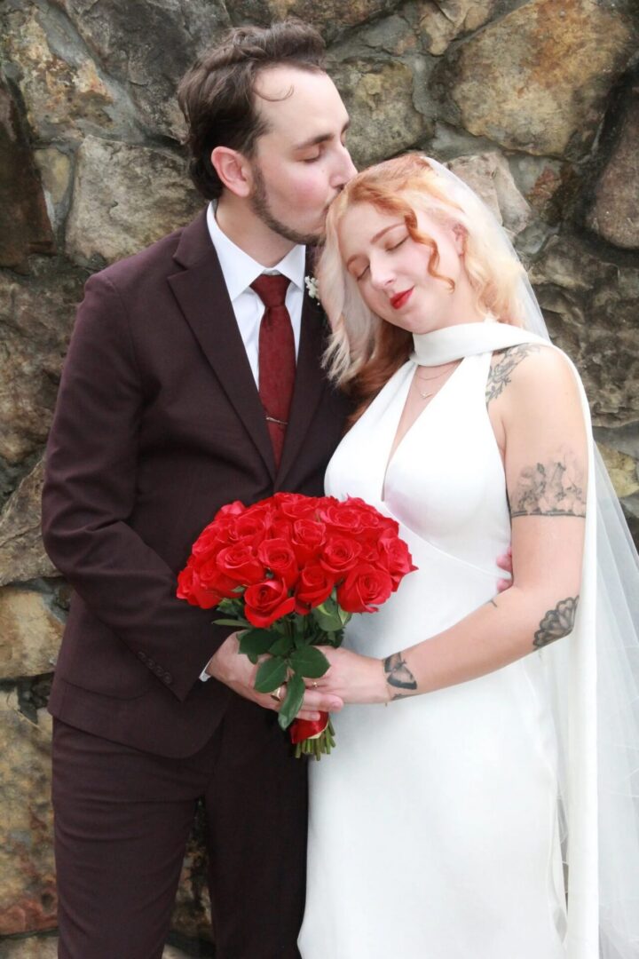 Bride and groom with red roses bouquet.