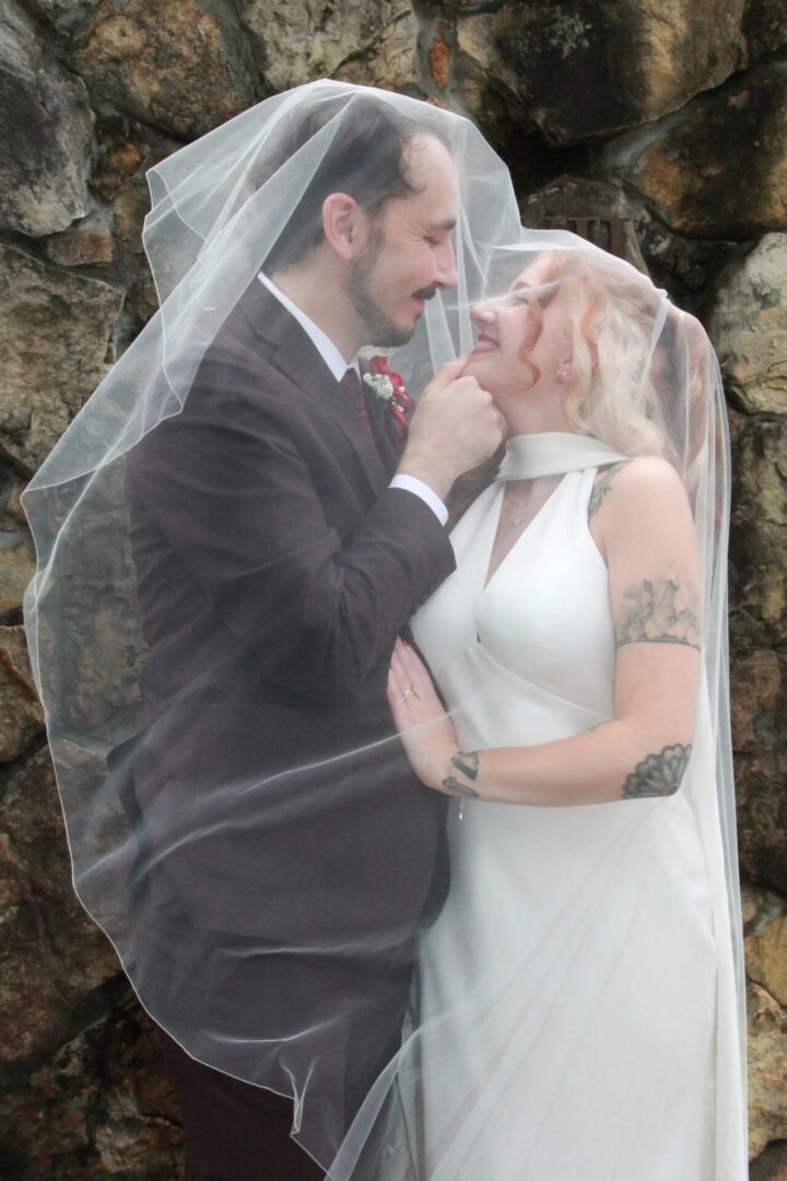 Bride and groom smiling under wedding veil.