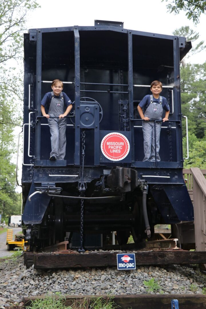 Two children standing on vintage train caboose.