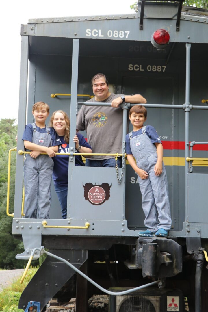 Family posing on a vintage train caboose.