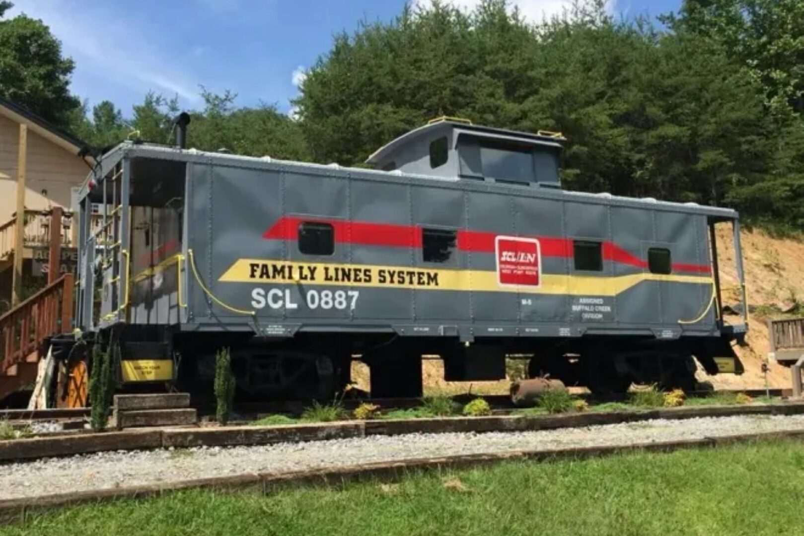Gray vintage train caboose on display outdoors.