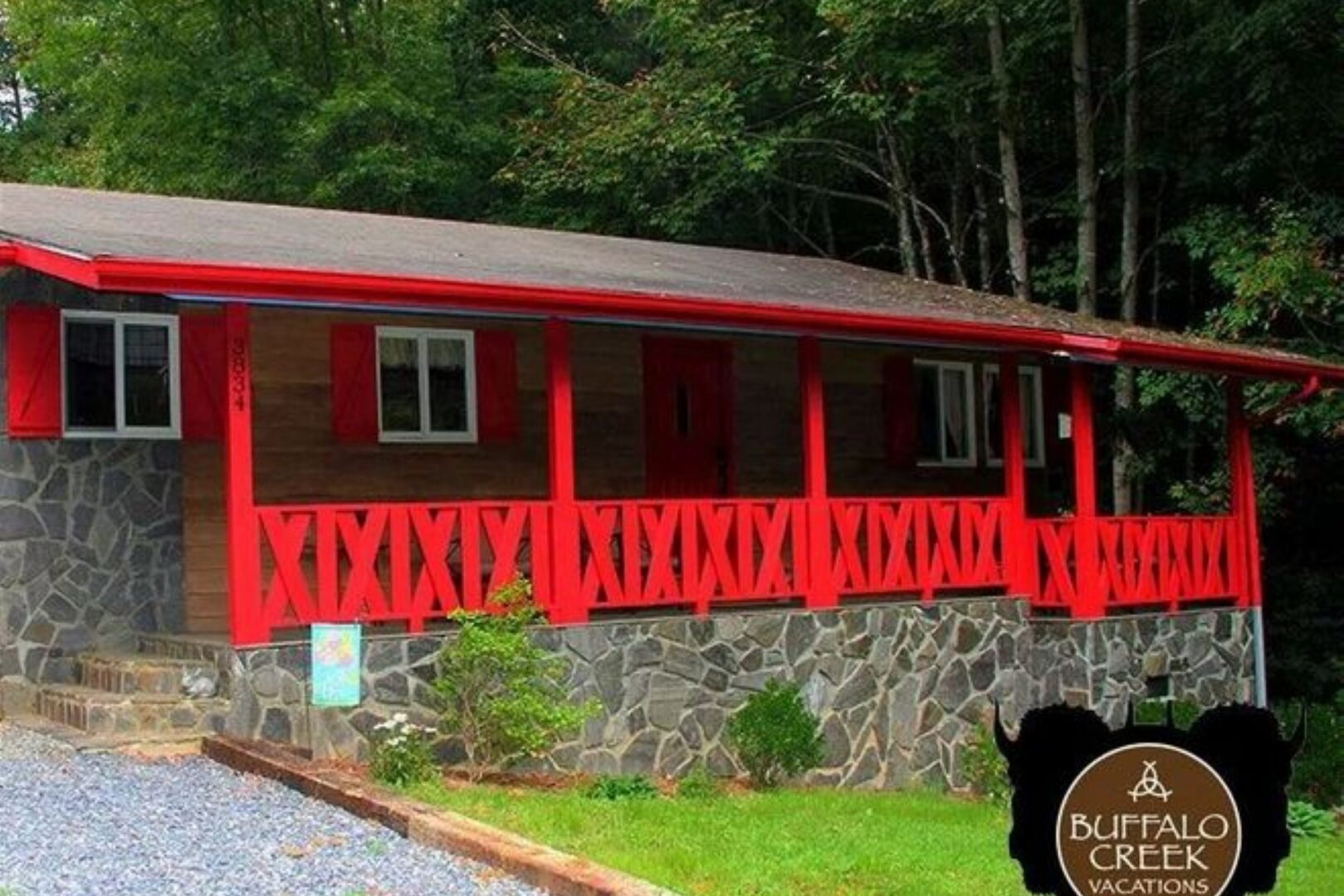 Red cabin with stone foundation and porch.