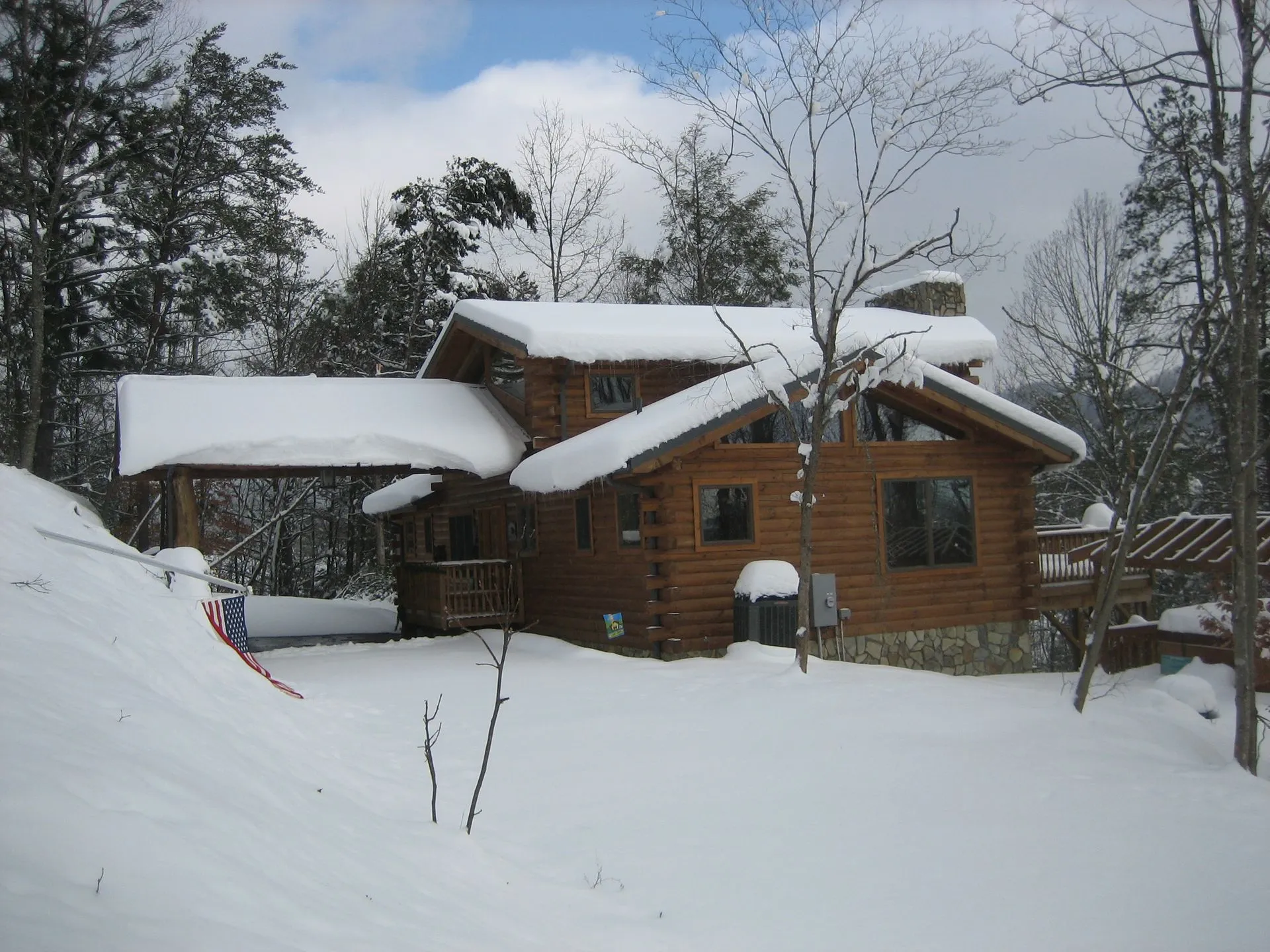 Snow-covered cabin surrounded by trees.