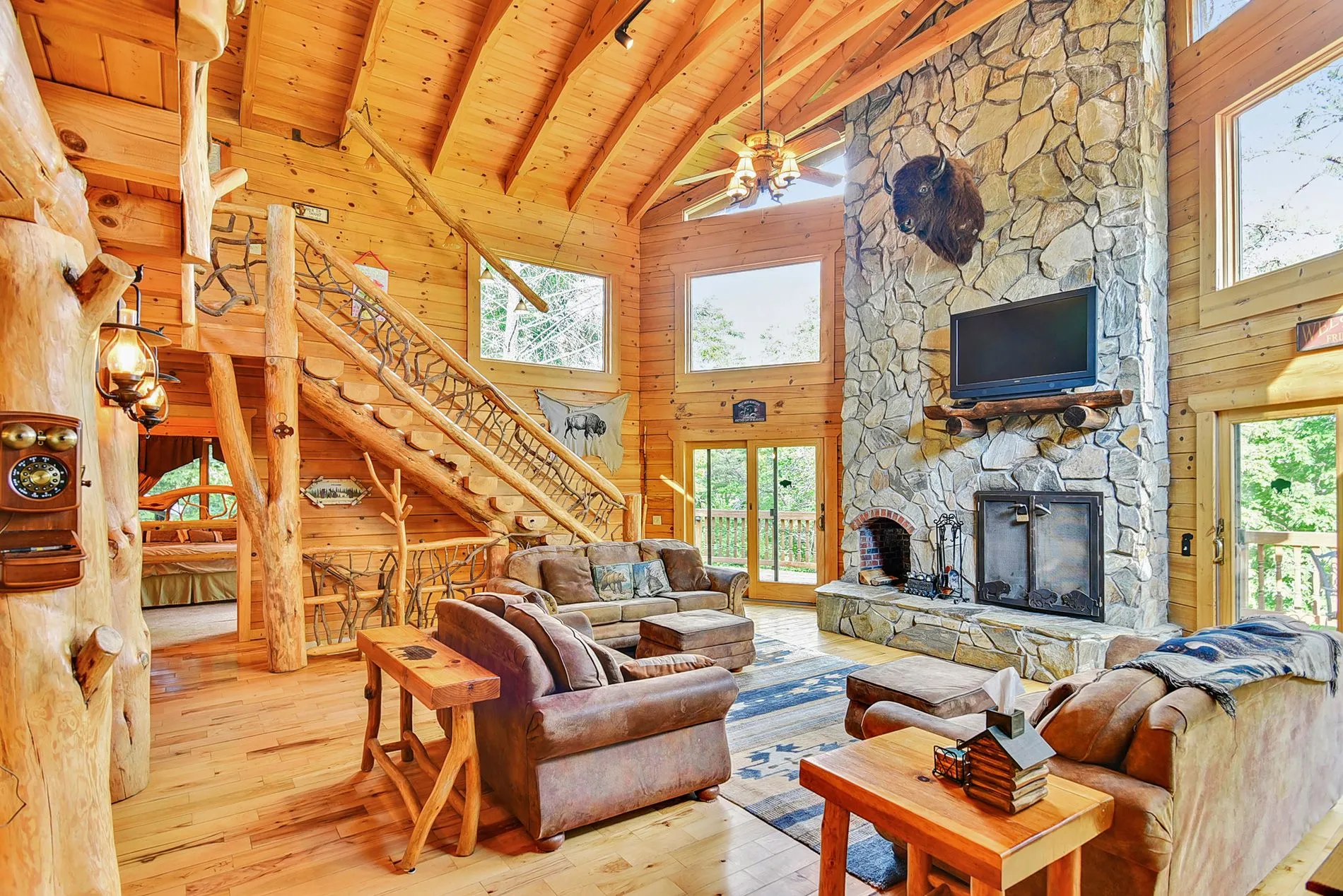 Rustic log cabin living room with stone fireplace.