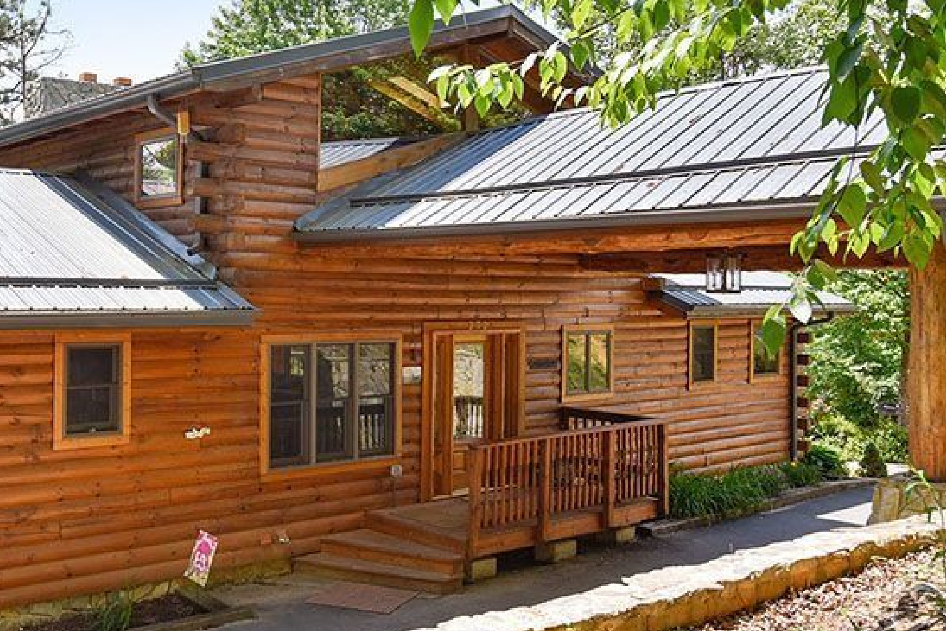 Wooden cabin with metal roof surrounded by trees.