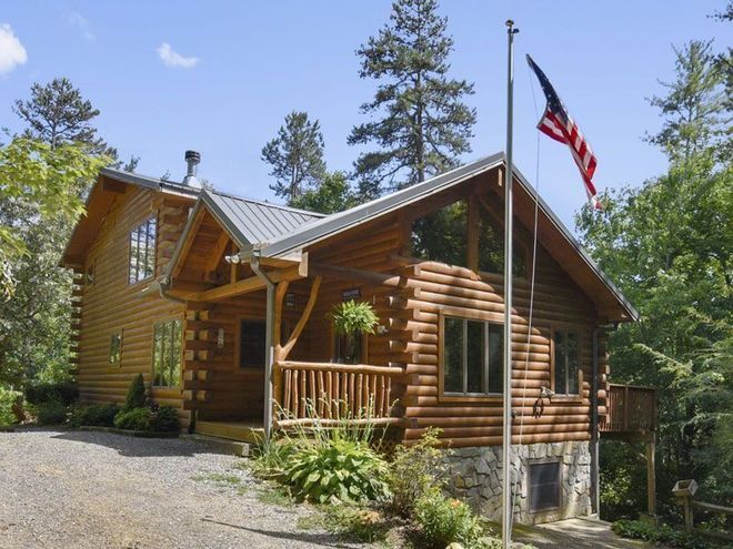 Log cabin with American flag and trees.