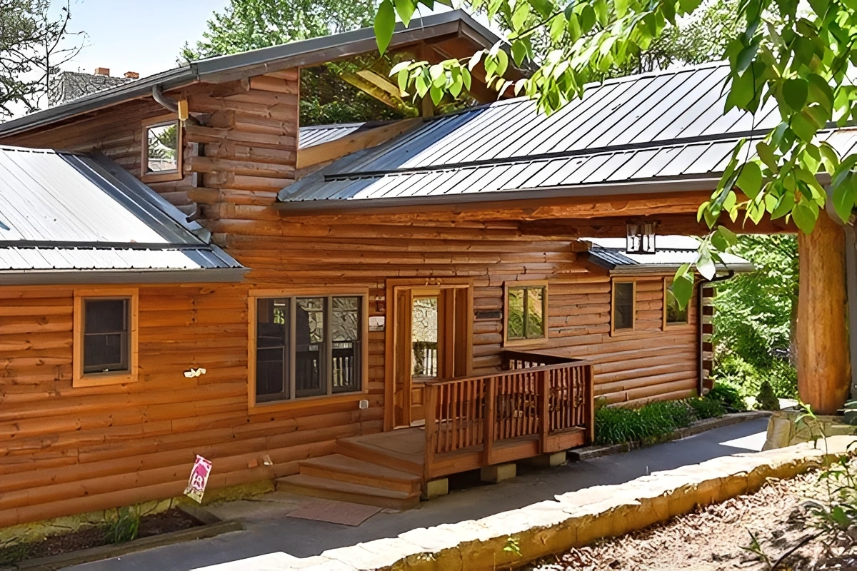 Log cabin with metal roof and trees.