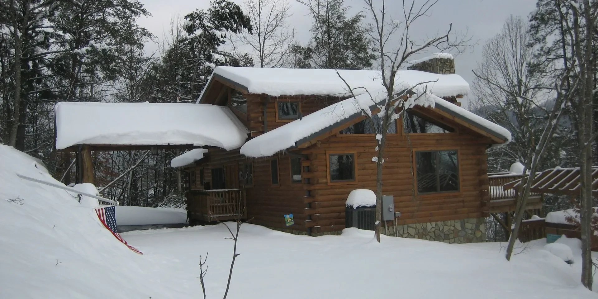 Snow-covered cabin surrounded by trees.